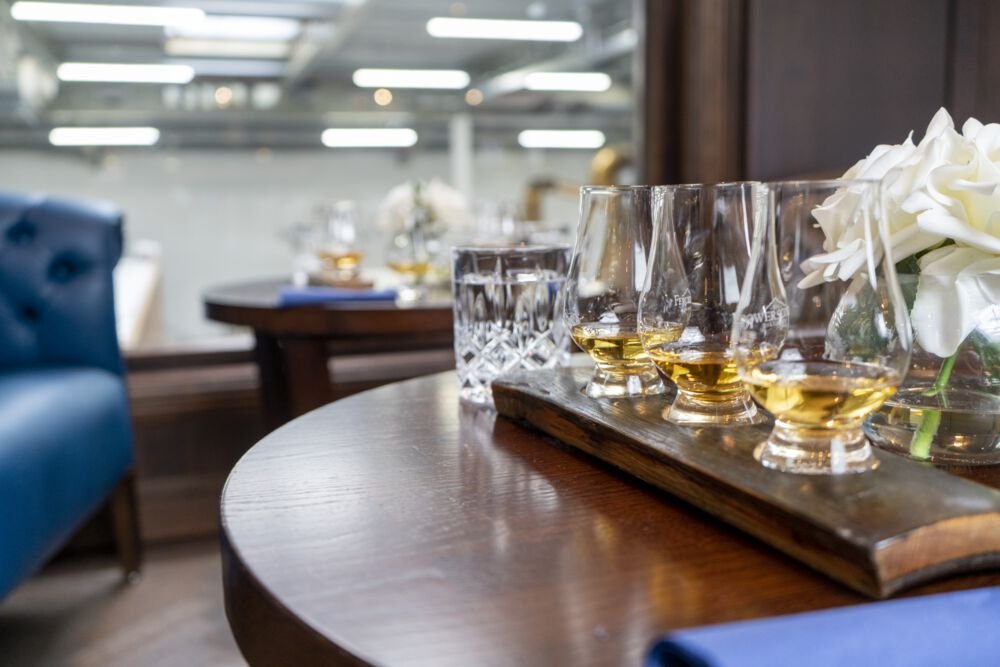 three glasses lined up with whiskey in them